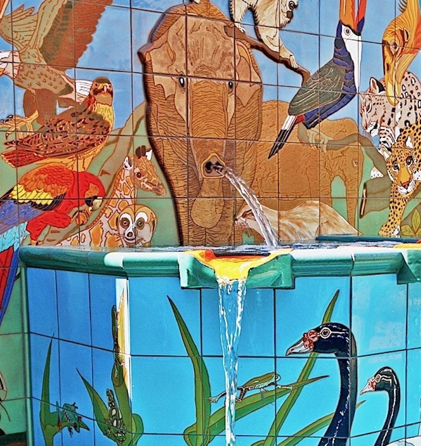 Detail: an elephant on the tiled wall, water pouring from its trunk into the fountain, with a macaw, a monkey and a toucan around it and a black swan on the plinth below.