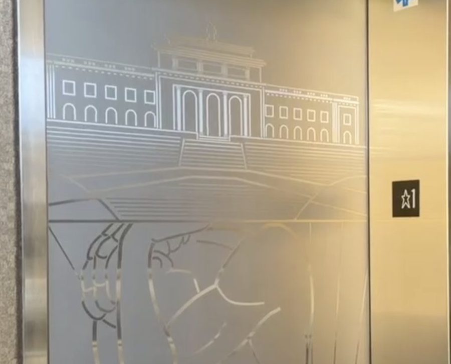 Detail of the etched elevator doors at 60 California Street: a fine incised line drawing of a neoclassical building with a colonnaded portico standing on a terrace, and beneath it the crouching figure of Atlas carrying his burden.
