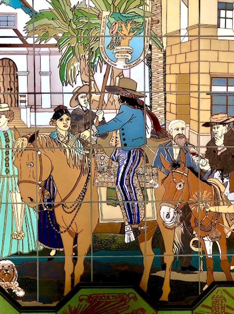 Detail of the upper register: riders on horseback carrying the San Buenaventura city seal on a banner, women in period dress, palms, the Mission facade at left, and a small shaggy dog at the lower left.