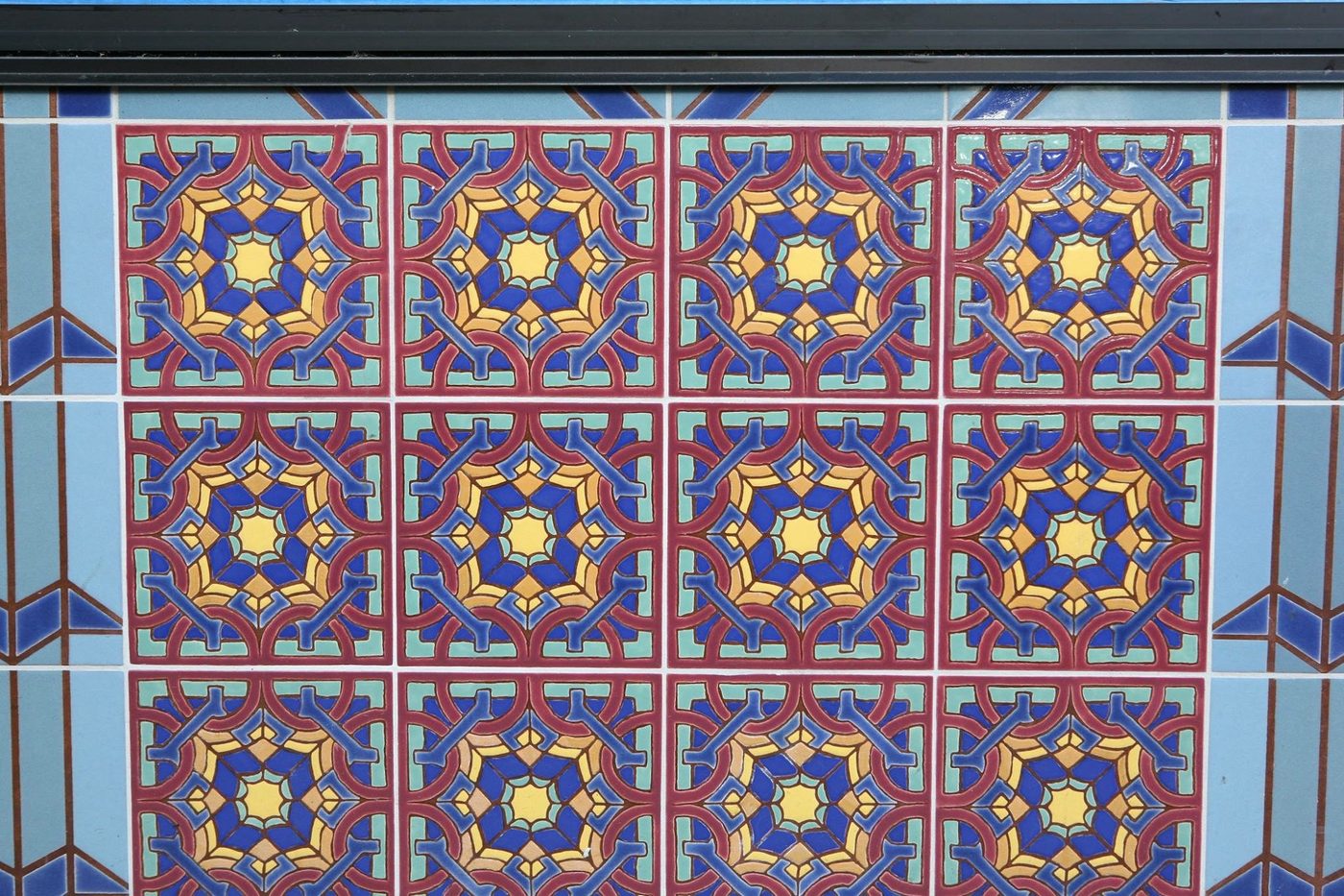 A panel of the building&rsquo;s tile: repeating eight-pointed stars in blue, gold and red.