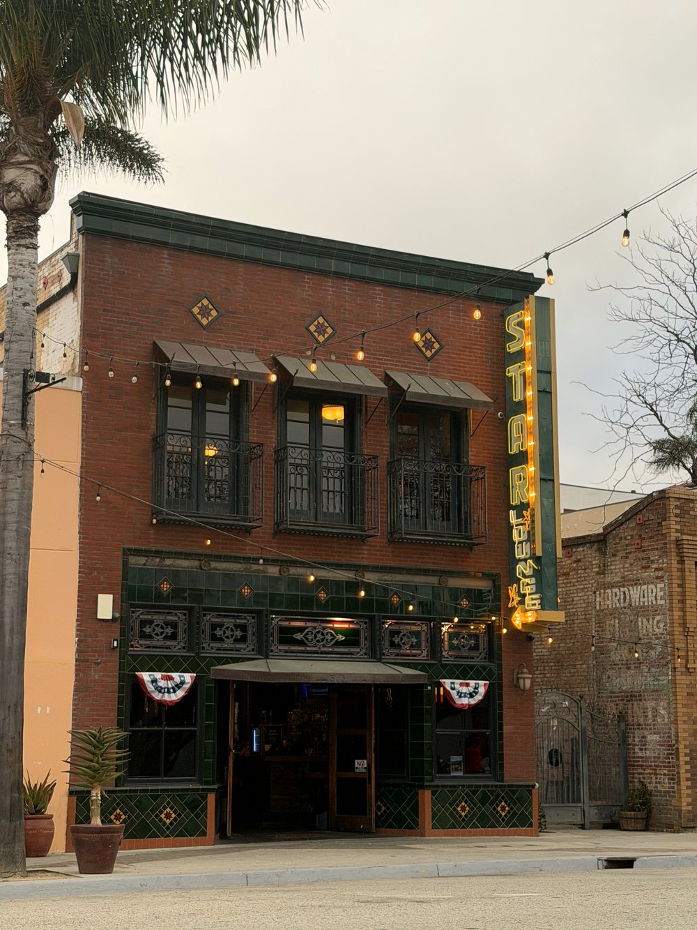 The Star Lounge building: red brick with three iron balconies and diamond tiles above a green tiled shopfront, with the tall STAR sign on the corner.