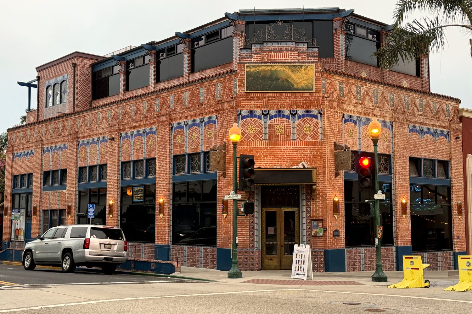 After: the Watermark today, with blue tile arches and patterned brick restored across both frontages of the building facade, and a new top floor clad to match.