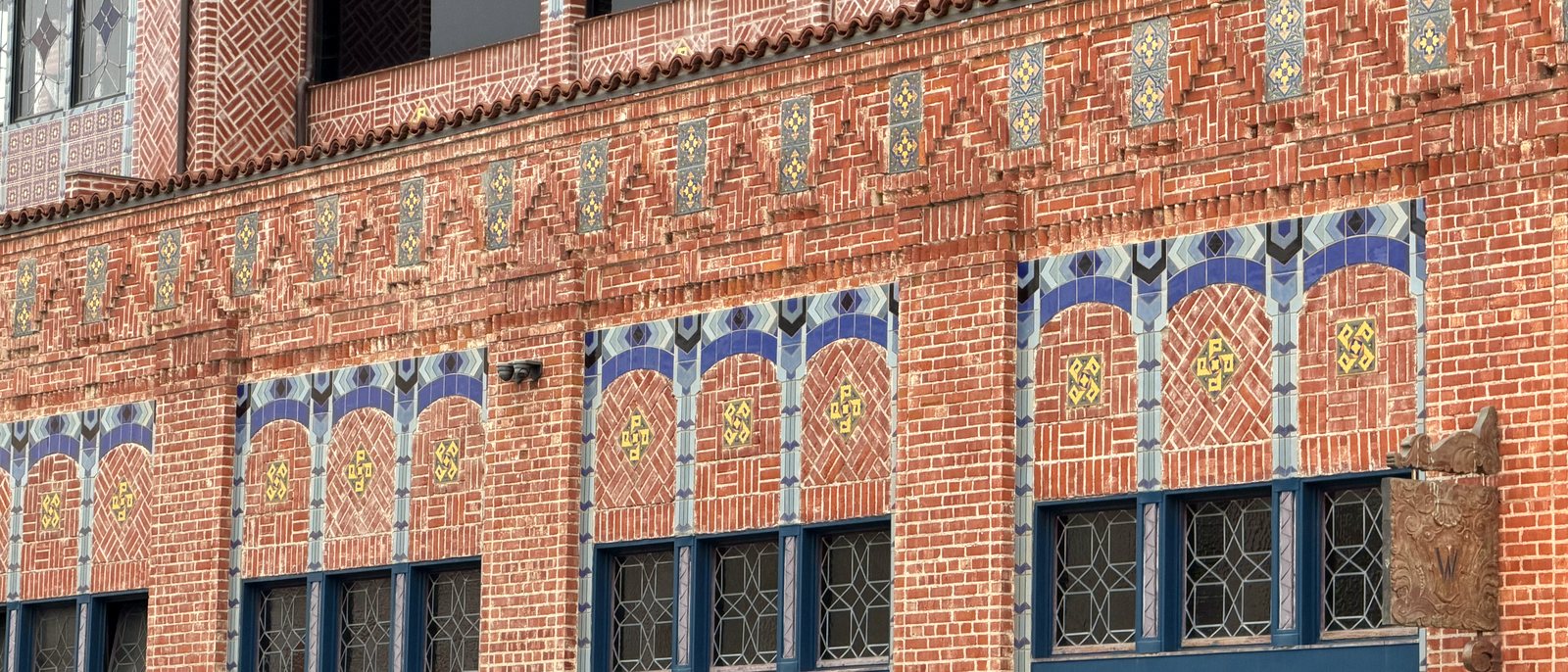 The California Street side of the Watermark: a long run of blue tile arches over the windows, set into bands of patterned brick.