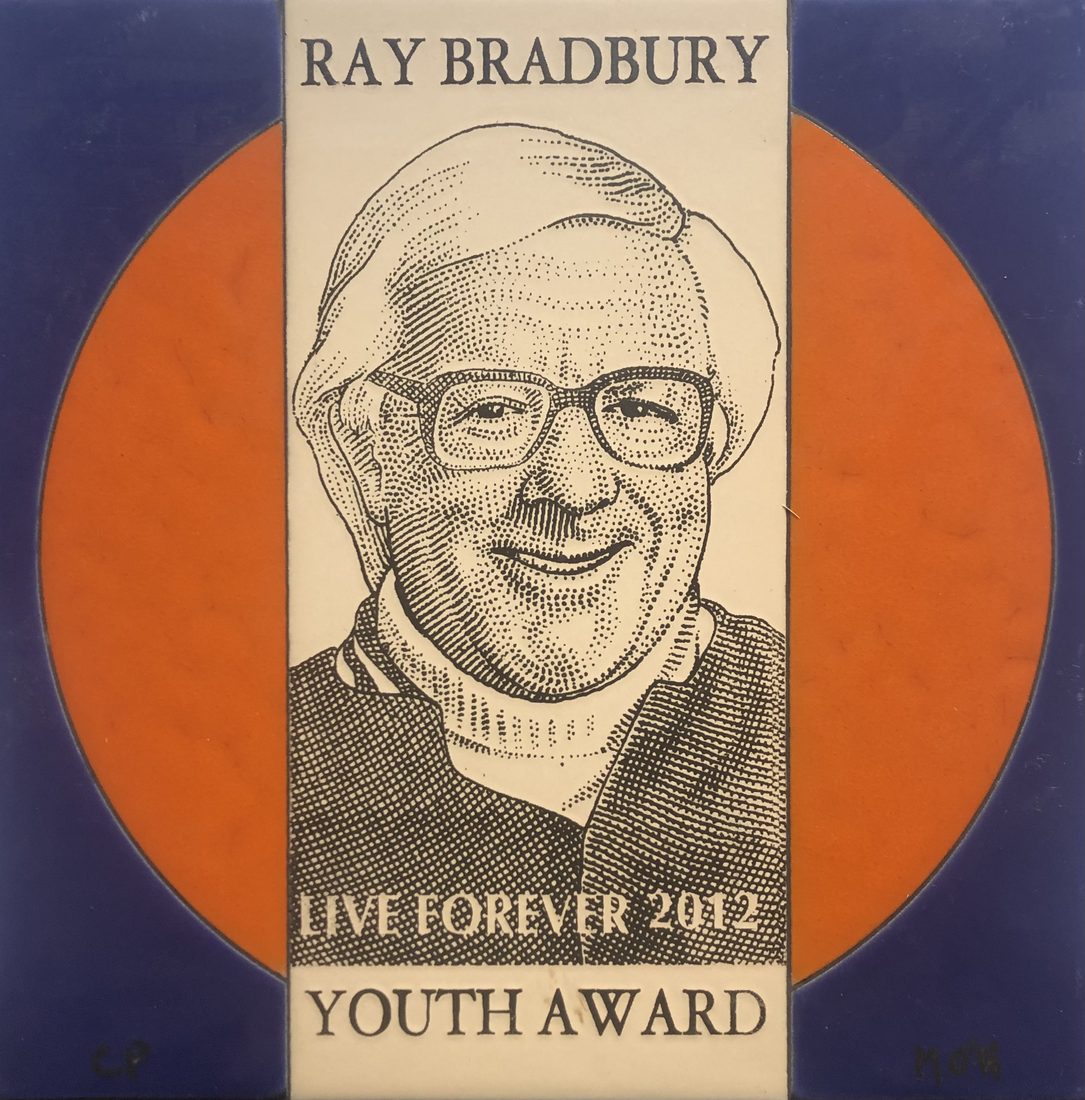 A ceramic plaque with a pen-and-ink portrait of Ray Bradbury on an orange sun, reading Ray Bradbury, Live Forever 2012, Youth Award.