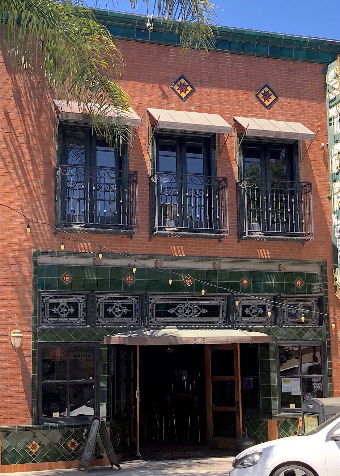 The Star Lounge in full sun, photographed by Michael O'Kelly: red brick, iron balconies and the green tiled shopfront.