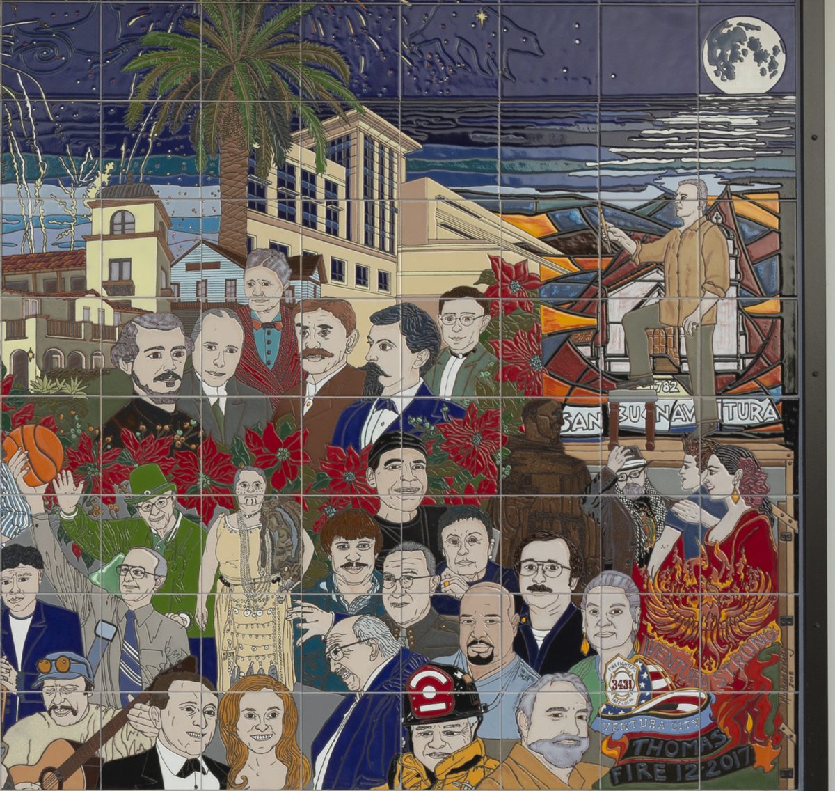 The last stretch of the mural at night: fireworks and a full moon over the sea, a crowd of present-day Venturans among poinsettias, a firefighter in a helmet, and a phoenix rising from flames above a banner reading Thomas Fire 12-2017.