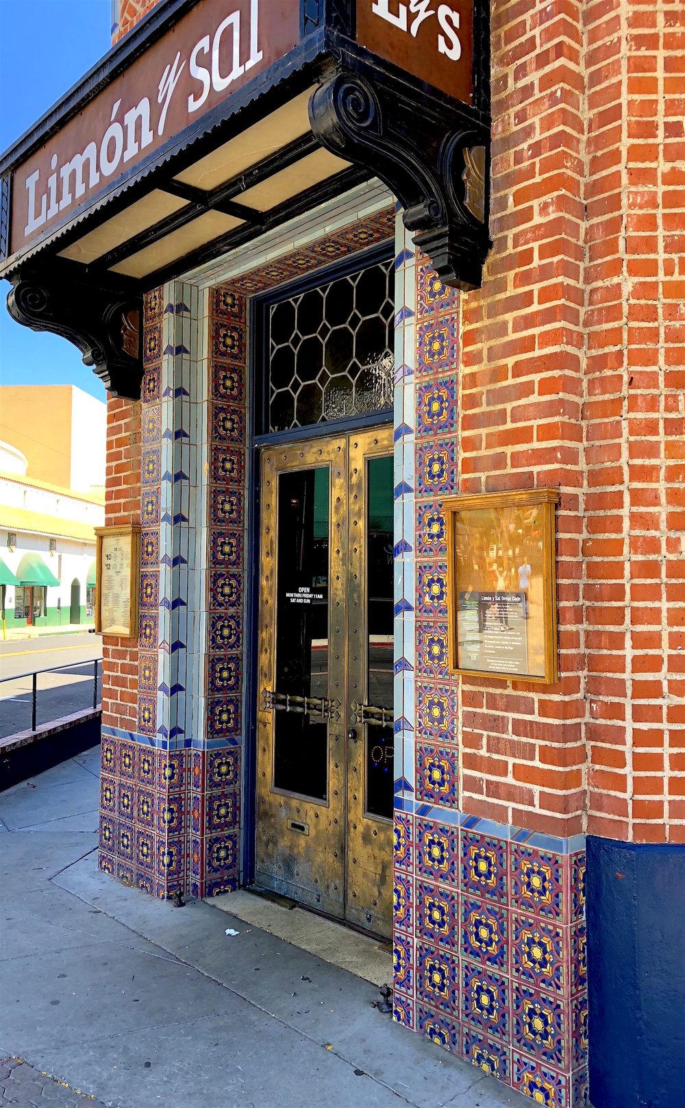 A doorway framed in patterned brick and tile, with a band of blue tile running up the side of the door, photographed by Michael O'Kelly.