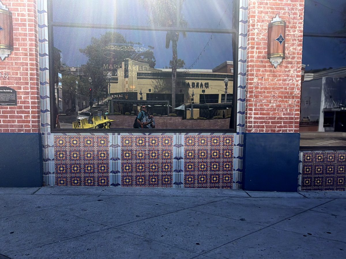 The wainscot under a shop window: a row of red and blue patterned tile panels between blue tile bands, at sidewalk level.