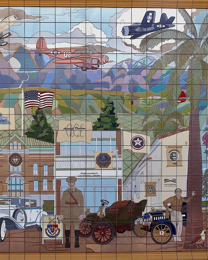 Detail of Giving Back at the Santa Barbara Foundation: aircraft over mountains above a street of early twentieth-century buildings and vintage cars, in glazed tile.